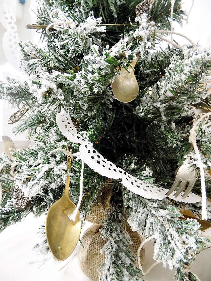 Vintage silver cuttlery on christmas tree, doily paper garland